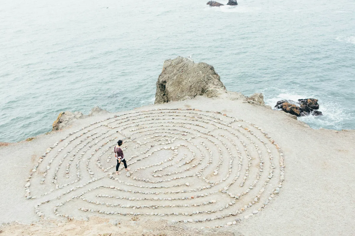 A person walking the path of a stone labyrinth laid out on a beach