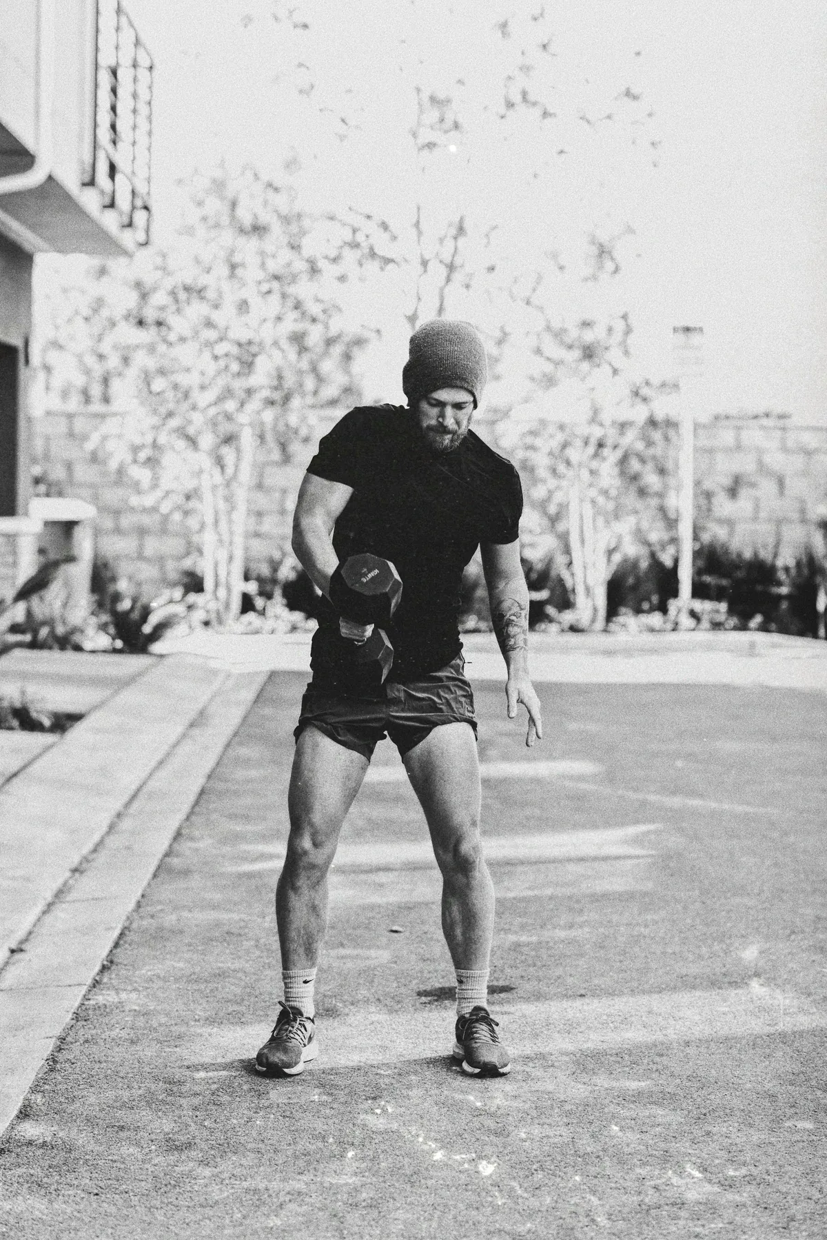 A man training with a kettlebell in a car park, in black and white